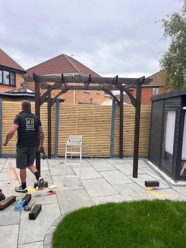 KJ Elite Construction worker building timber pergola on stone patio